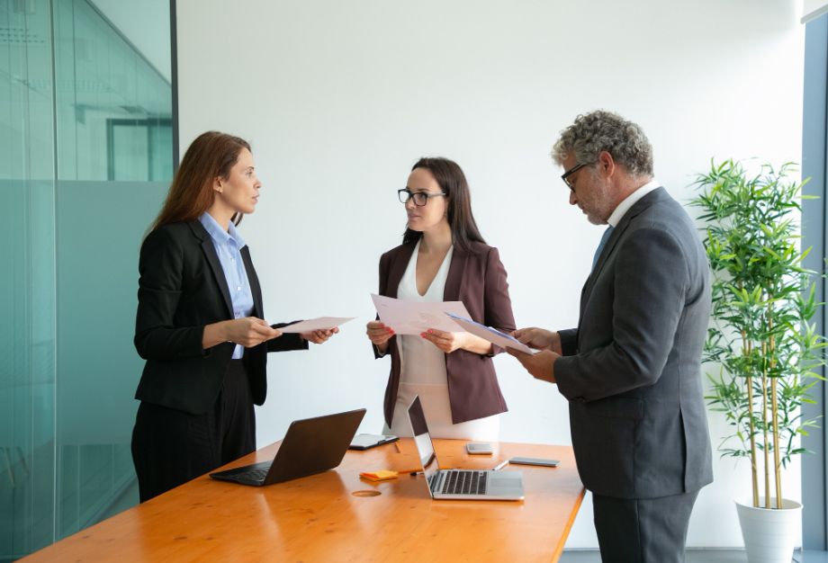 Tres profesionales discutiendo documentos en una oficina moderna
